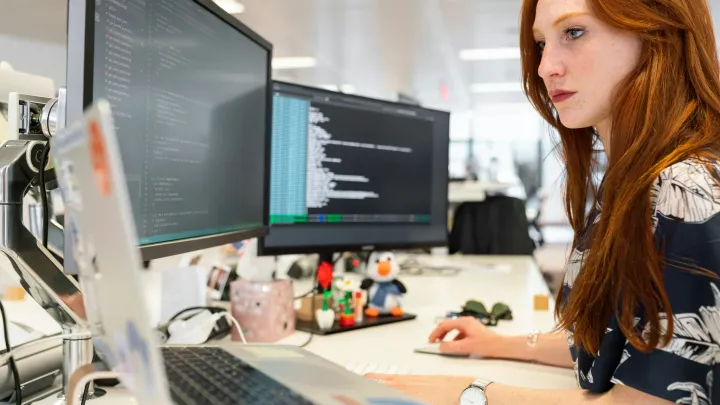 Ingénieur logiciel comparant du code et des sorties d’exécution sur plusieurs écrans