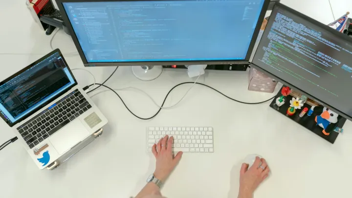 Ingénieur logiciel travaillant sur trois écrans de terminal